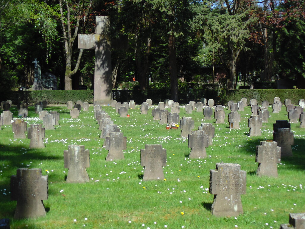 Sicht auf das Kriegsgräberfeld Nr. 90 auf dem Kölner Friedhof Melaten (2020). Im Hintergrund ist das alles überragende und brutalistisch gehaltene Kreuz der Anlage zu sehen.