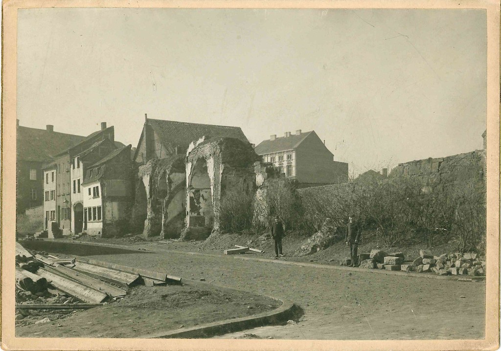 Die frei stehenden Reste der Dürener Stadtmauer in der Wallstraße auf einer historische Aufnahme (vermutlich Anfang des 20. Jahrhunderts), dahinter Wohnhäuser.