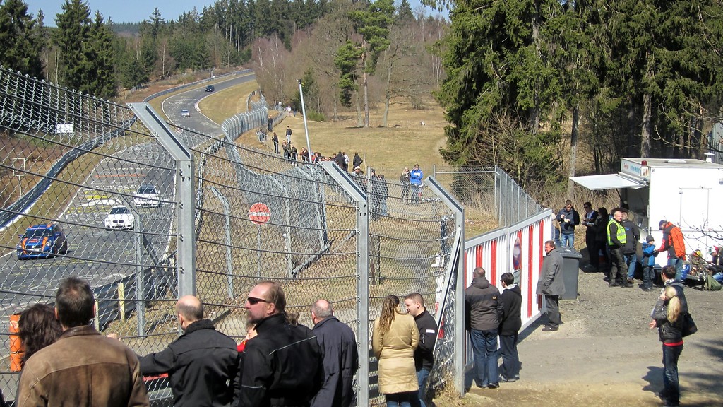 Streckenabschnitt "Pflanzgarten" der Nürburgring-Nordschleife (2013). Zuschauer verfolgen hinter Sicherheitsabsperrungen private Fahrzeuge bei Touristenfahrten ("Jedermann-Rennen")