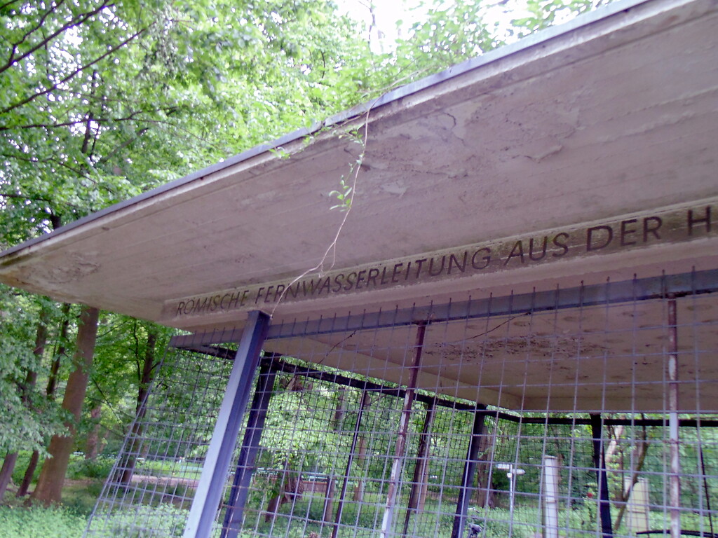 Inschrift (Teil I) am Schutzbau des ehemaligen Absetzbecken der römischen Eifelwasserleitung in Köln-Sülz (2021).