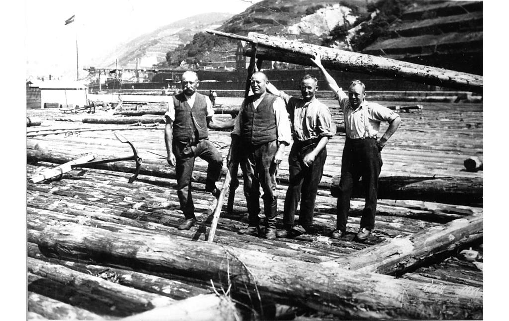 Vier Männer auf einem Rheinfloß, der zweite von links hält einen Lappen, eine seitliche Ruderstange (um 1910)
