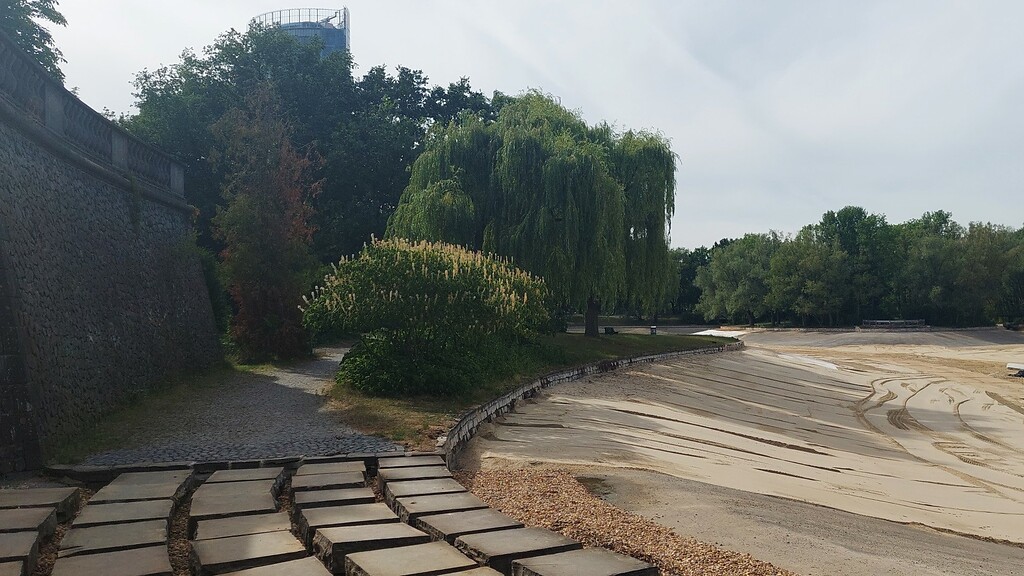 Rheinauenpark in Bonn-Gronau (2022), der 15 Hektar große Rheinauensee wurde im Zuge einer umfassenden Sanierung trockengelegt. Im Hintergrund das Hochhaus "Post-Tower" der Deutschen Post AG.