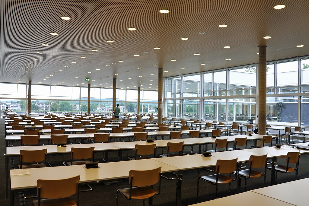 Ansicht des Lesesaals der Universitäts- und Landesbibliothek Bonn (ULB) mit vollständig verglasten Fassaden, die am rechten Rand den Blick in den Innenhof der ULB freigeben und im Hintergrund die gegenüberliegende Beueler Rheinuferseite zeigen (2017).