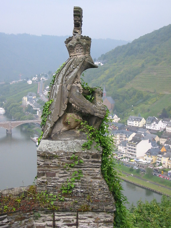 Reichsburg Cochem: Detailansicht einer steinernen Skulptur, die einen gekrönten Frosch mit Umhang darstellt. Im Hintergrund die Mosel und der Cochemer Ortsteil Cond (2002).