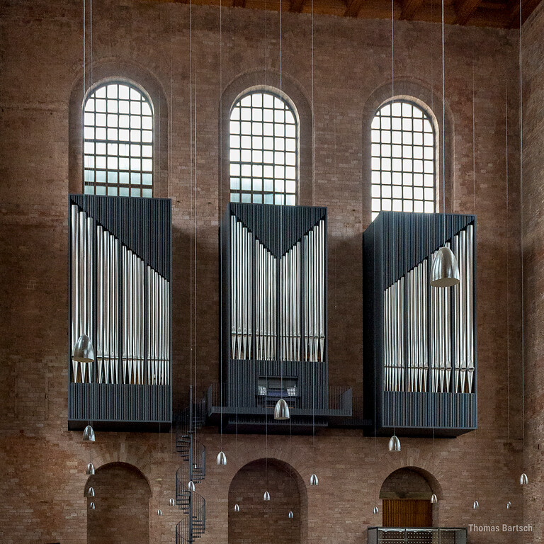 Die 2014 eingeweihte neue Hauptorgel der heute als protestantische Kirche genutzten Konstantinbasilika in Trier (2022). Das Instrument hängt an der Südwand der einstigen römischen Palastaula und ist auf drei Gehäusekörper verteilt, die sich in die Fensternischen einfügen.
