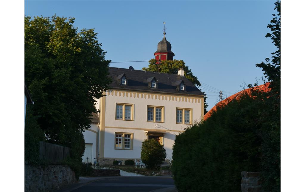 Südliche Ansicht des alten Pfarrhauses in Dörrebach mit dem Turm der katholischen Kirche (2016)