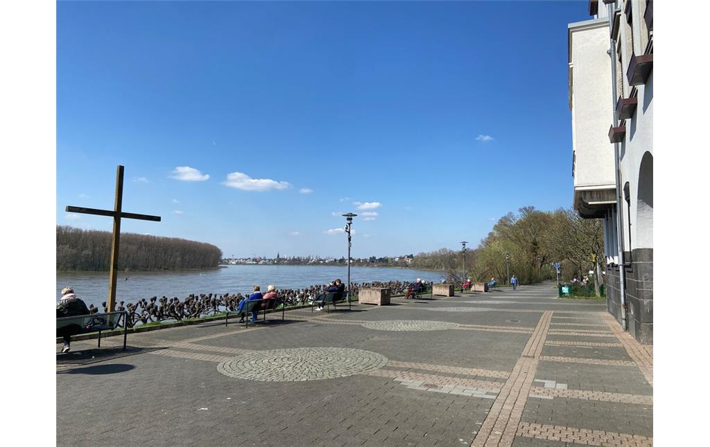 Das Friedrich-Ebert-Ufer in Porz auf Höhe des Rathauses mit dem hölzernen Weltjugendtagkreuz, das am Pfingstwochenende 2023 stark beschädigt wurde (Foto: April 2023). Die Straße ist hier nur für Fußgänger*innen zugänglich. Blick nach Norden in Richtung Köln.