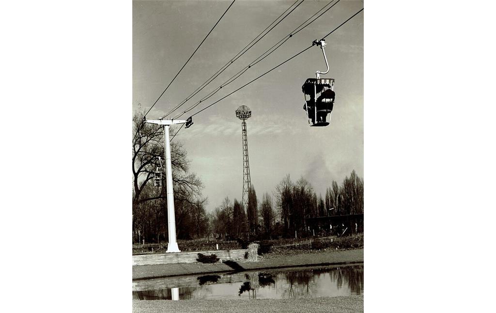 Historische Aufnahme (zwischen 1957 und 1963): Eine Gondel und ein Mast der "kleinen" Sesselbahn im Rheinpark Deutz, dahinter der Fordturm.