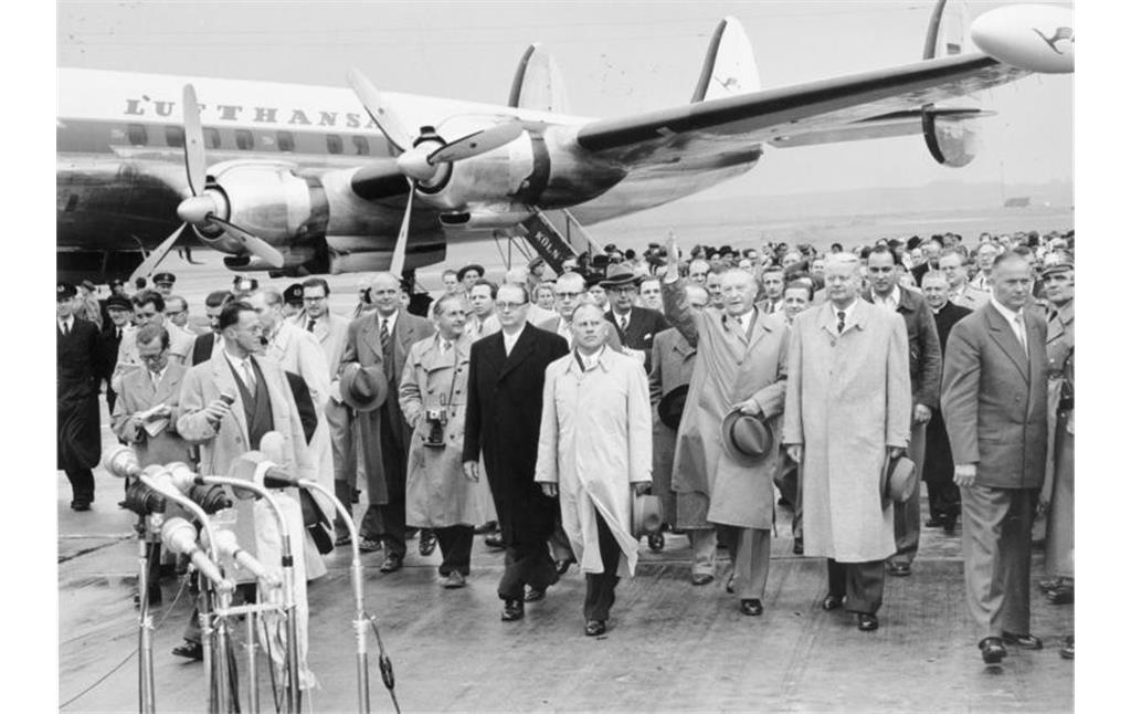 Rückkehr der Delegation um Bundeskanzler Konrad Adenauer nach der Moskau-Reise, bei der die Freilassung der letzten 9.626 deutschen Kriegsgefangenen aus dem Zweiten Weltkrieg erreicht wurde (14. September 1955 auf dem Flughafen Köln-Wahn). Im Hintergrund das viermotorige Verkehrsflugzeug "Lockheed Super Constellation" der Lufthansa (Kennung D-ALIN), mit dem die Reise durchgeführt wurde.