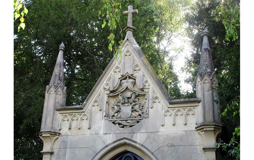 Der von einem Kreuz bekrönte Giebel der Familiengruft mit dem Wappenschild der Grafen Berghe von Trips auf dem Friedhof Kerpen-Horrem (2022).