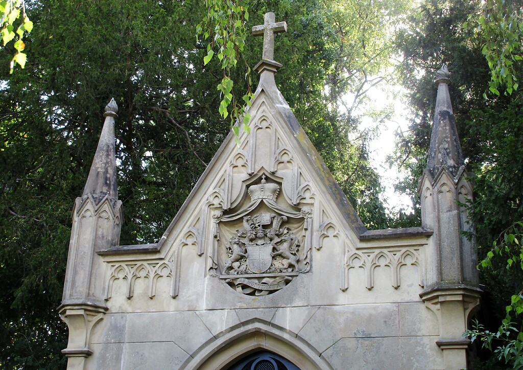 Der von einem Kreuz bekrönte Giebel der Familiengruft mit dem Wappenschild der Grafen Berghe von Trips auf dem Friedhof Kerpen-Horrem (2022).