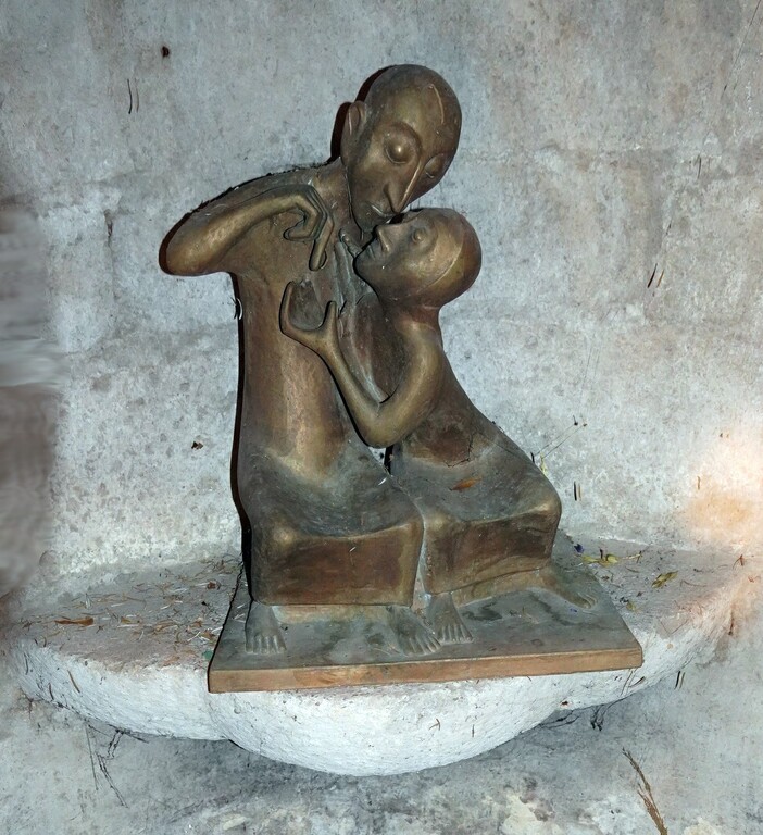 Die Bronzefigur in Form eines Tröstenden in der Brunnennische des "Kunibertspütz" in der Krypta unterhalb der Kirche des Kunibertstifts in Köln-Altstadt-Nord (2023).