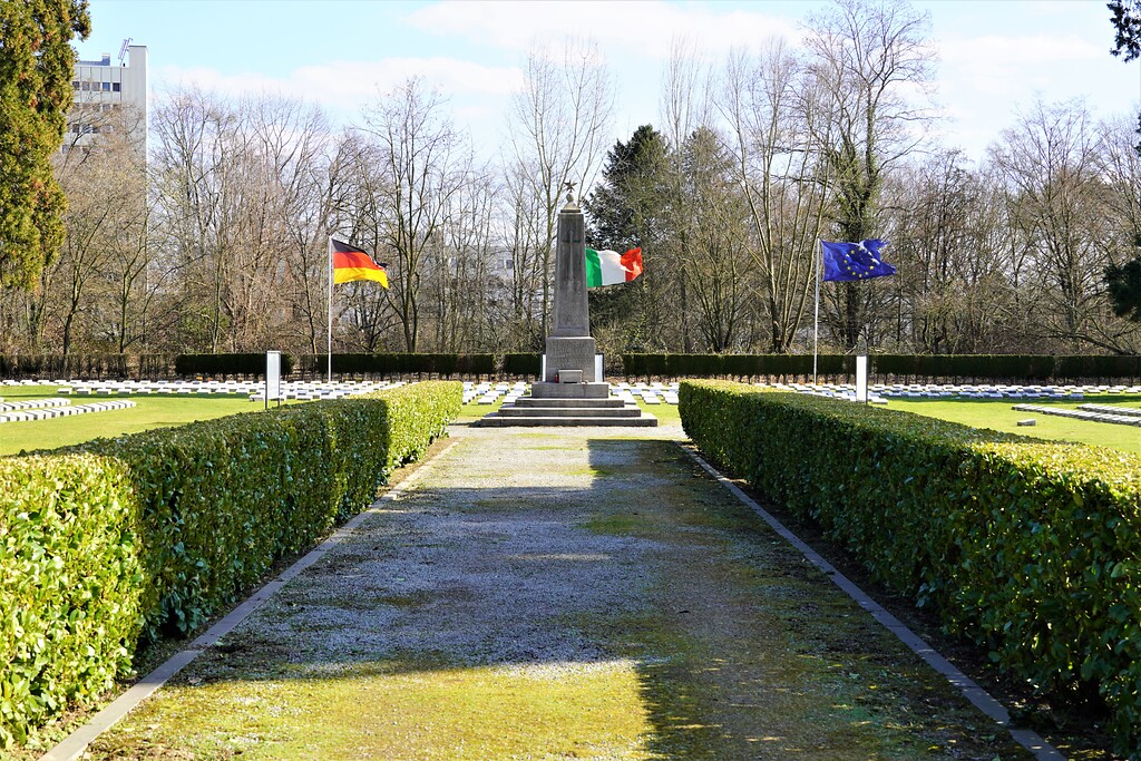 Der italienische Ehrenfriedhof auf dem Kölner Südfriedhof in Köln-Zollstock, Blick auf die Hauptachse mit Fahnen und Obelisk (2023).
