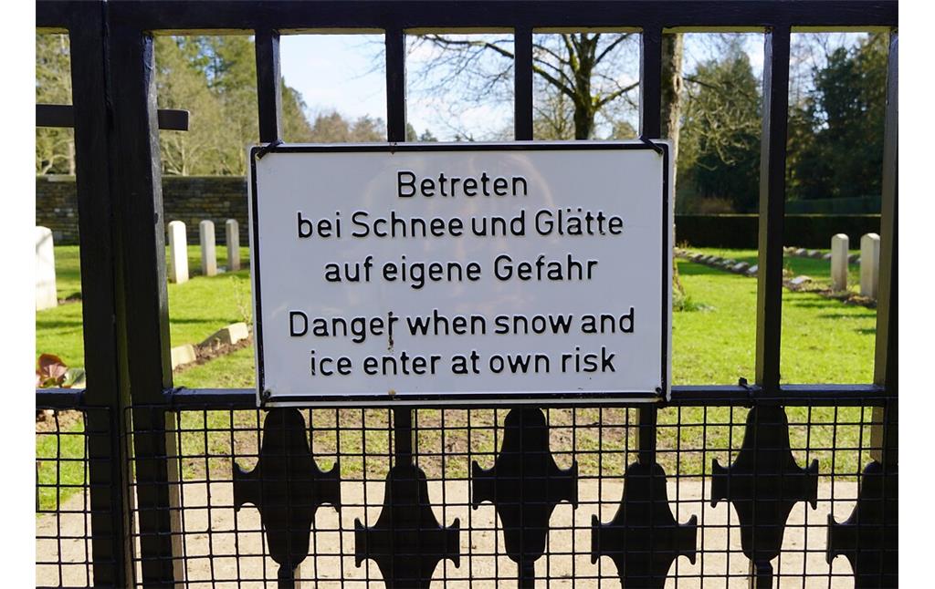 Zweisprachiges Hinweisschild am Eingang des Britischen Ehrenfriedhofes auf dem Kölner Südfriedhof in Köln-Zollstock (2023).
