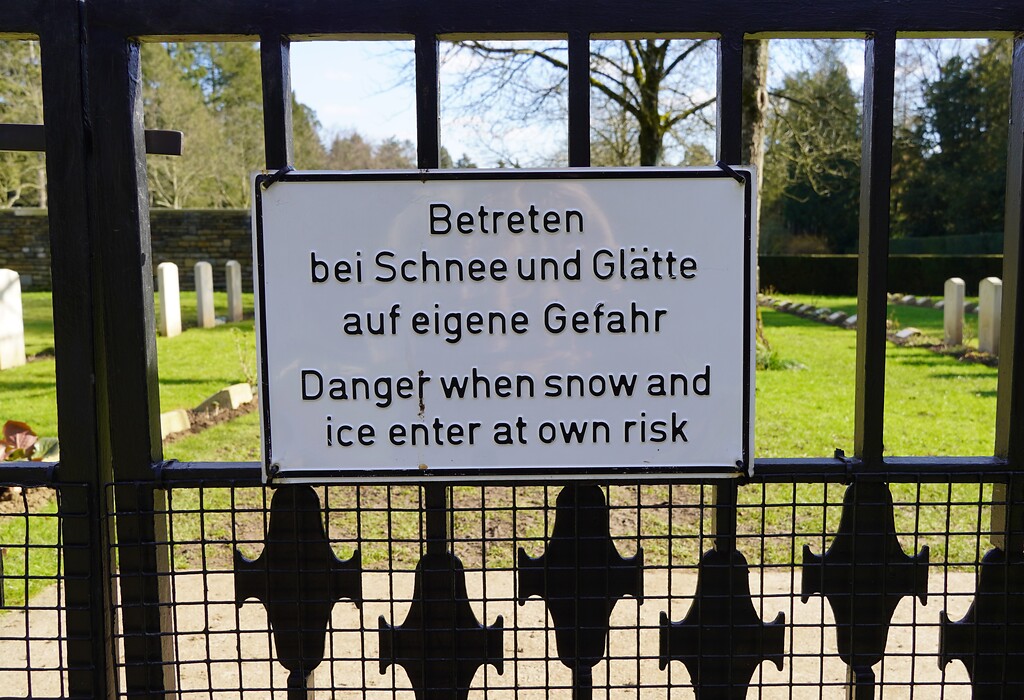 Zweisprachiges Hinweisschild am Eingang des Britischen Ehrenfriedhofes auf dem Kölner Südfriedhof in Köln-Zollstock (2023).