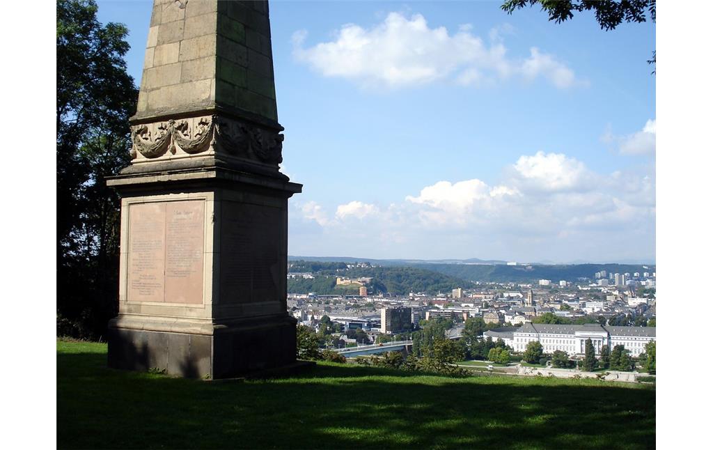 Der untere Teil des Kriegerdenkmals (Obelisk) für die Gefallenen Soldaten des Feldzuges von 1866 in Asterstein in Koblenz. Im Hintergrund sind die Pfaffendorfer Rheinbrücke und Teile des linksrheinischen Koblenz zu erkennen (2014).