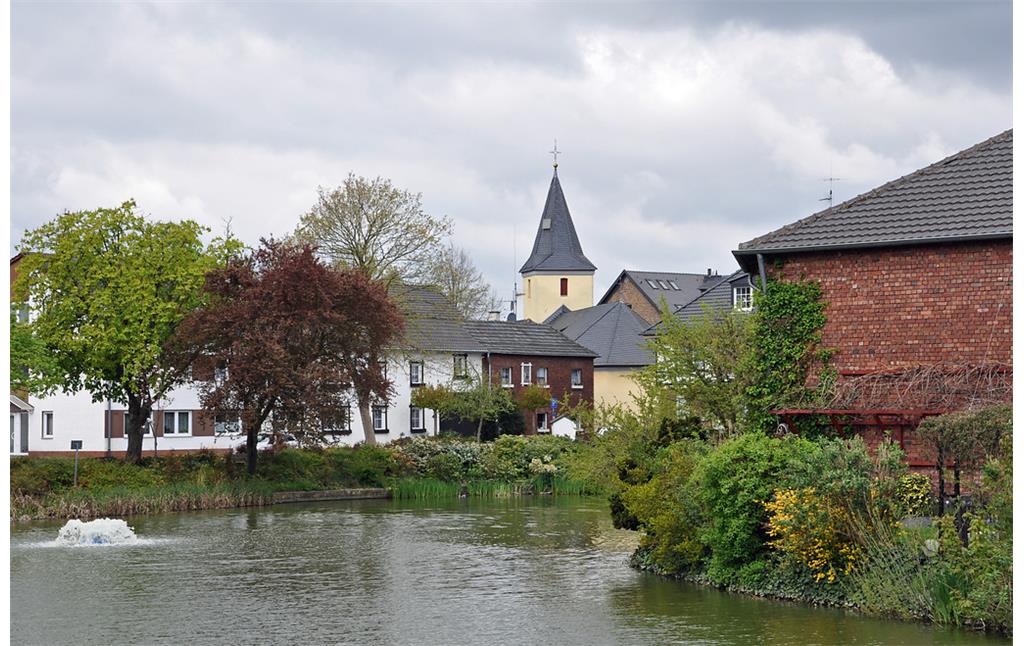 Burgweiher innerhalb des historischen Ortskerns von Buschhoven mit Versöhnungskirche (2016)
