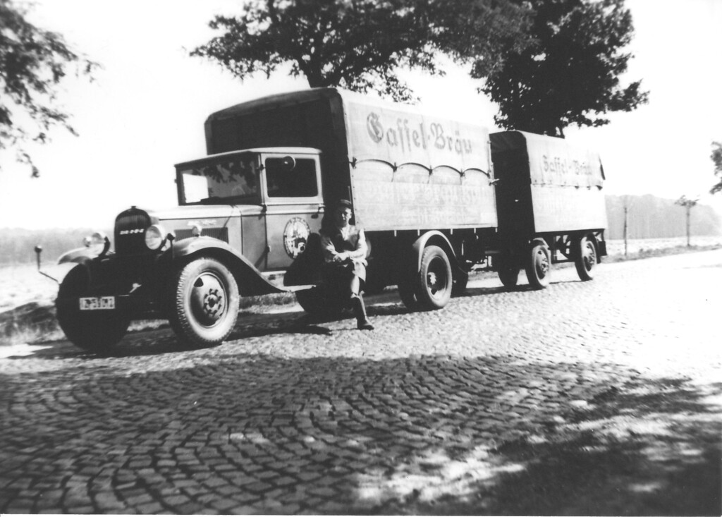 Ein Mann (vermutlich ein Mitarbeiter der Gaffel-Brauerei) sitzt auf dem Trittbrett der Fahrerkabine eines Lastwagens. Auf dem Lastwagen und dem Anhänger steht "Gaffel-Bräu" (Datum unbekannt).