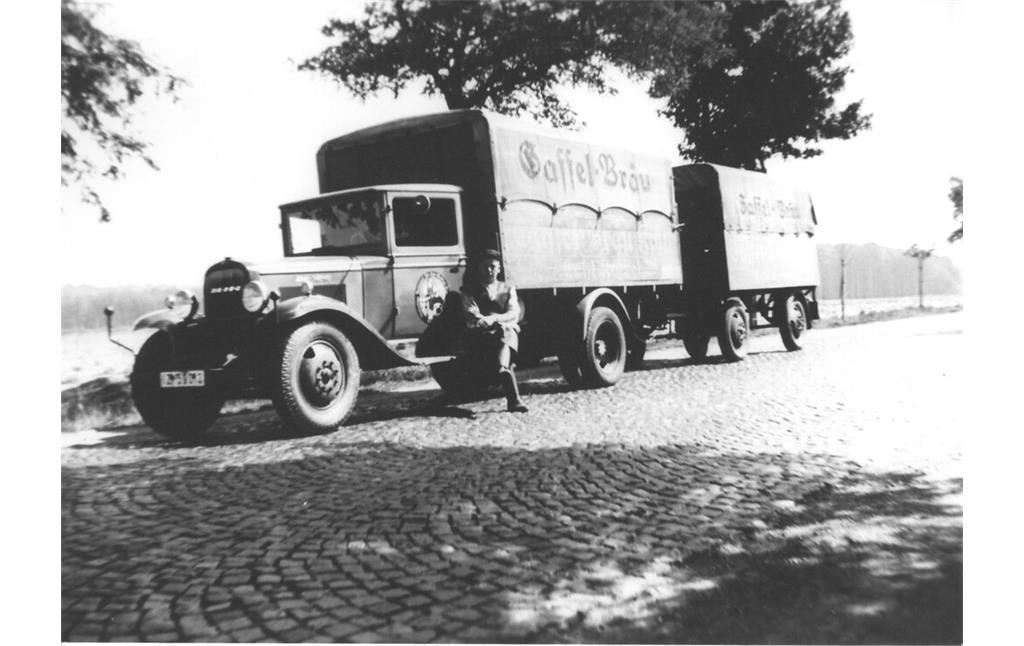 Ein Mann (vermutlich ein Mitarbeiter der Gaffel-Brauerei) sitzt auf dem Trittbrett der Fahrerkabine eines Lastwagens. Auf dem Lastwagen und dem Anhänger steht "Gaffel-Bräu" (Datum unbekannt).