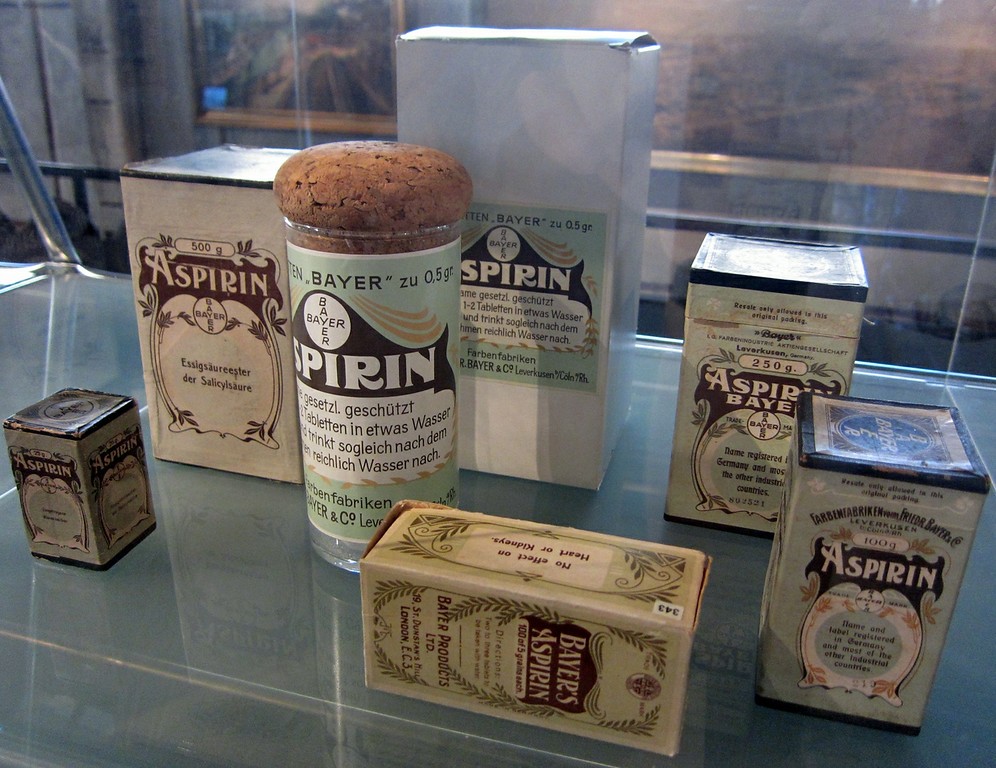 Verschiedene Verpackungen des Medikaments "Aspirin" der Firma Bayer aus den Jahren 1899-1912 mit dem 1904 beim Kaiserlichen Patentamt als Warenzeichen eingetragenen Bayer-Kreuz (in der LVR-Verbundausstellung "1914 - Mitten in Europa", 2014).