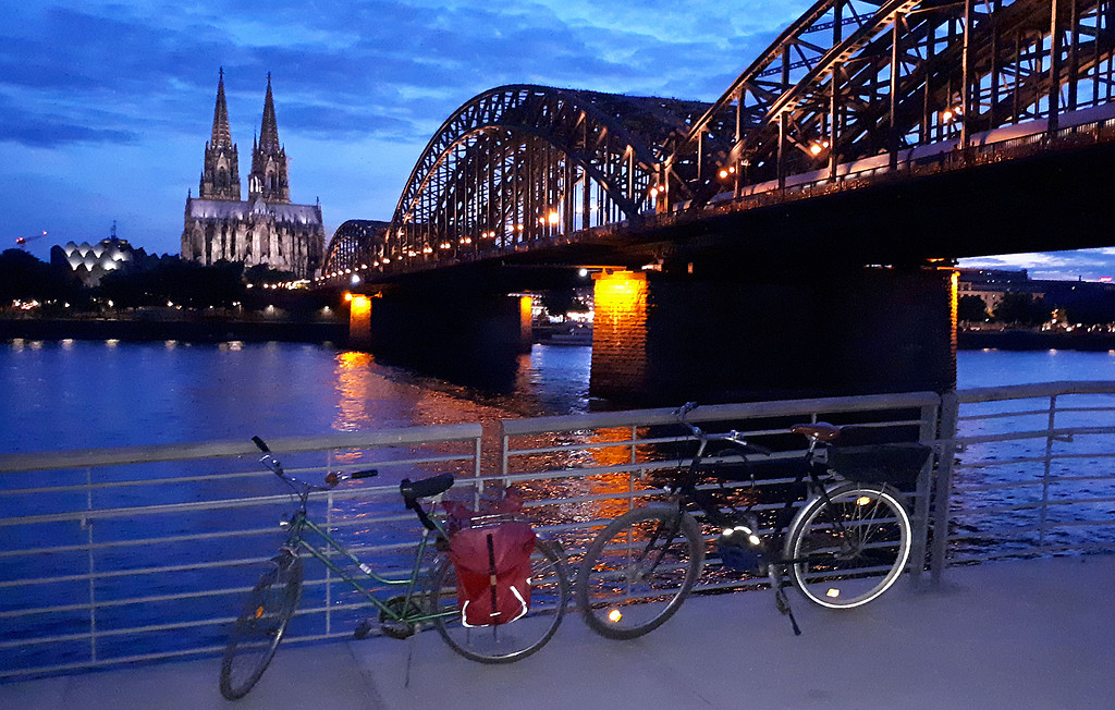 Abendlicher Blick von Deutzer Rheinboulevard aus entlang der Hohenzollernbrücke auf Köln mit dem Dom und der Philharmonie links (2019).