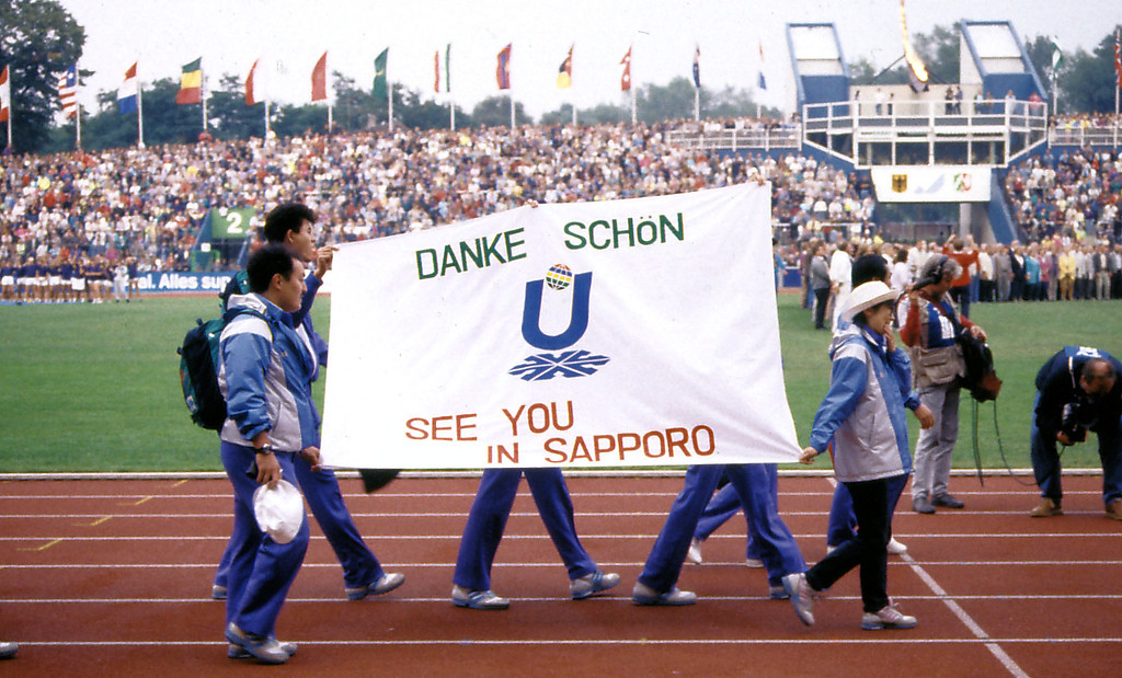 Sommer-Universiade 1989 im Duisburger Wedaustadion: Eine Gruppe von Sportlern trägt am Ende der Weltsportspiele der Studenten ein "Danke schön"-Transparent über die Laufbahn des Stadions.