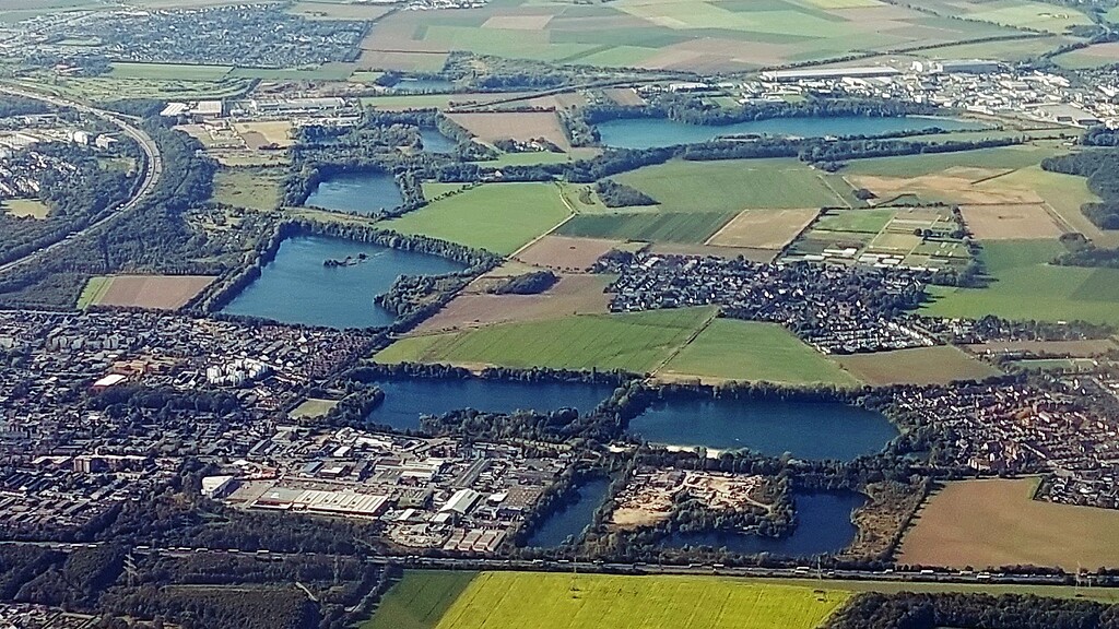Luftbildaufnahme von Köln-Esch/Auweiler in westliche Blickrichtung (2021), zentral rechts im Bild das Dorf Auweiler umrahmt von den umgebenden Seen.