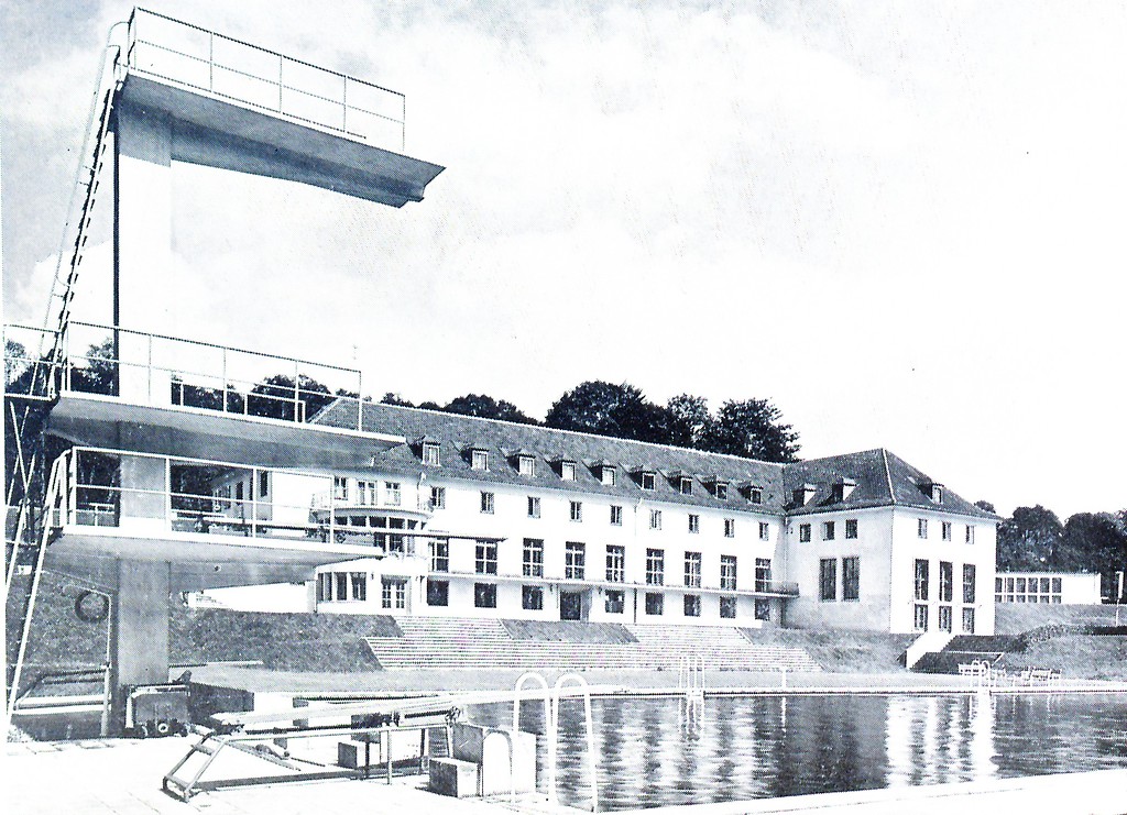 Blick vom Freibad mit Sprungturm auf das Hauptgebäude der Sportschule Hennef, im Hintergrund die Sporthalle (Aufnahme vor 1960).