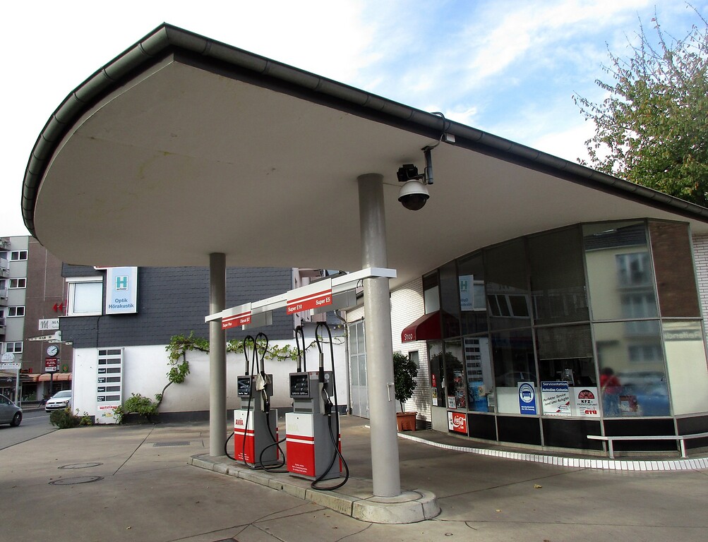 Historische AVIA-Tankstelle in Köln-Rodenkirchen (2022): Über den Zapfsäulen ein für die Nachkriegszeit typisches, von zwei Säulen getragenes Spannbeton-Dach, dahinter das kleine Kassenhäuschen.