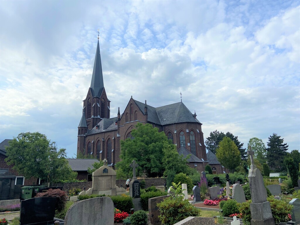 Blick auf die heutige Pfarrkirche St. Mariae Geburt in Köln-Zündorf vom Friedhof Niederzündorf aus (2023).