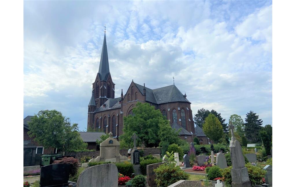 Blick auf die heutige Pfarrkirche St. Mariae Geburt in Köln-Zündorf vom Friedhof Niederzündorf aus (2023).