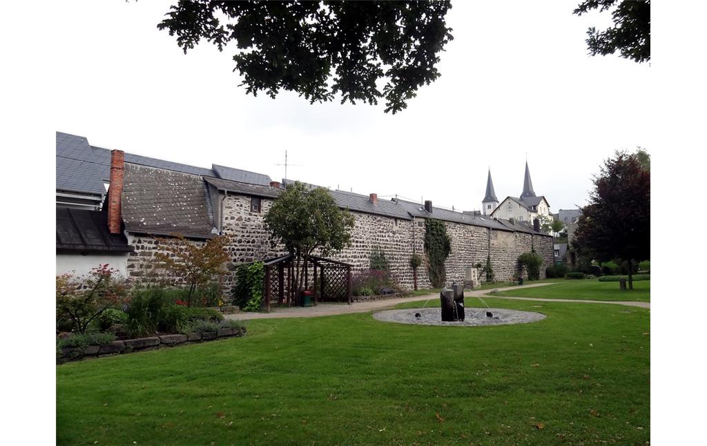 Teil der ehemaligen Stadtmauer von Montabaur. Vor der Mauer befindet sich eine kleine Parkanlage mit Brunnen (2014)