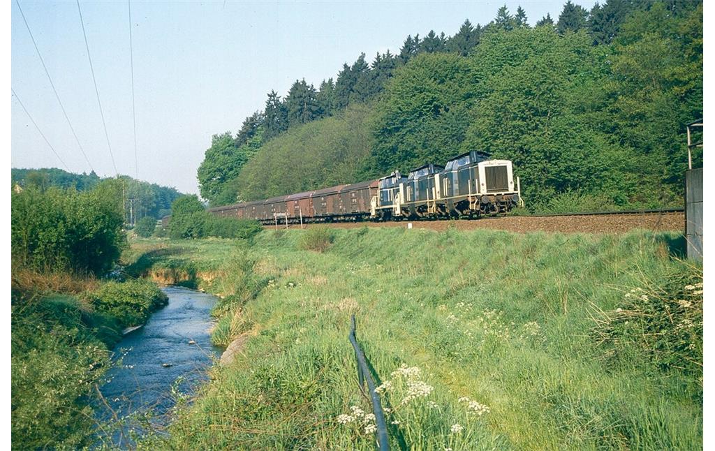Drei dieselhydraulische Lokomtiven der Baureihe V 100 der Deutschen Bundesbahn ziehen einen Güterzug auf der Strecke der Brexbachtalbahn (vermutlich 1980er Jahre).