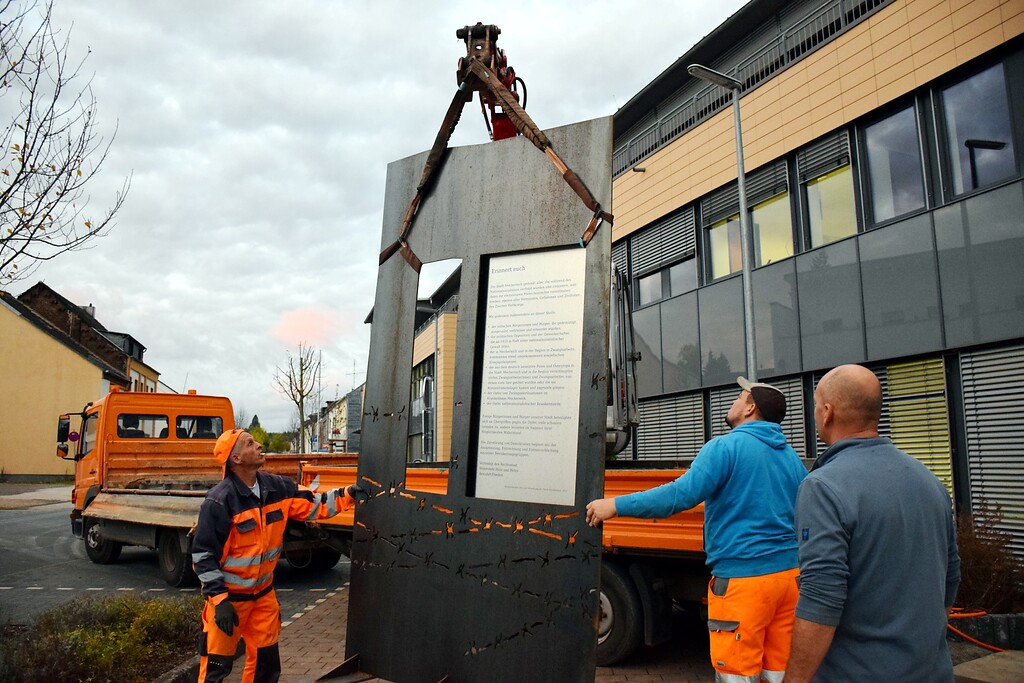 Bild 5: Die großformatige und schwere Stele wird mit einem Bagger vorsichtig vom LKW vor das Rathaus gehoben.