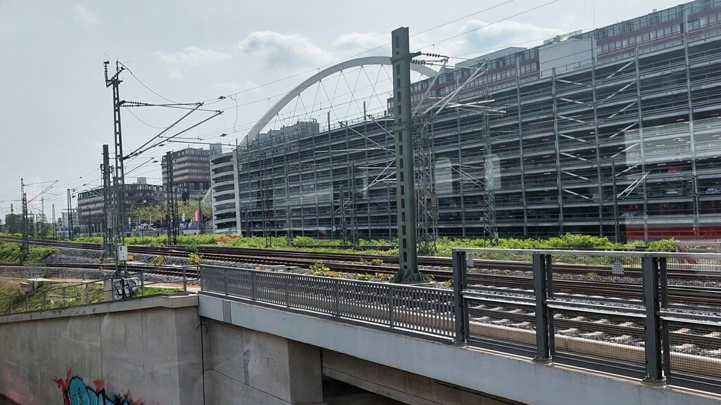 Zugeinfahrt in den Bahnhof Köln Messe/Deutz mit Blick auf das Parkhaus des Stadthauses Deutz und den Bogen der wegen diesem auch "Henkelmännchen" genannten Lanxess-Arena (2024).