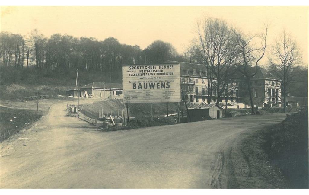 Straßenarbeiten an der Sövener Straße im Dürresbachtal bei Hennef, im Hintergrund der Rohbau der Sportschule, Ansicht von Norden (Aufnahme 1949).