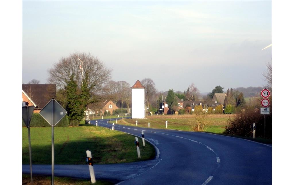Südansicht des Transformatorengebäudes in Schermbeck-Besten, der Weiße Turm Besten an der Kirchhellener Straße, im Hintergrund das Dorf Besten (2014).