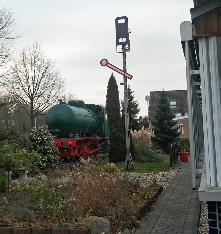 Alte Dampfspeicherlok und ein Eisenbahnsignal auf dem Gelände des ehemaligen Kleinbahnhofs Ost in Elsdorf neben dem "Café Dampflok" (2018).
