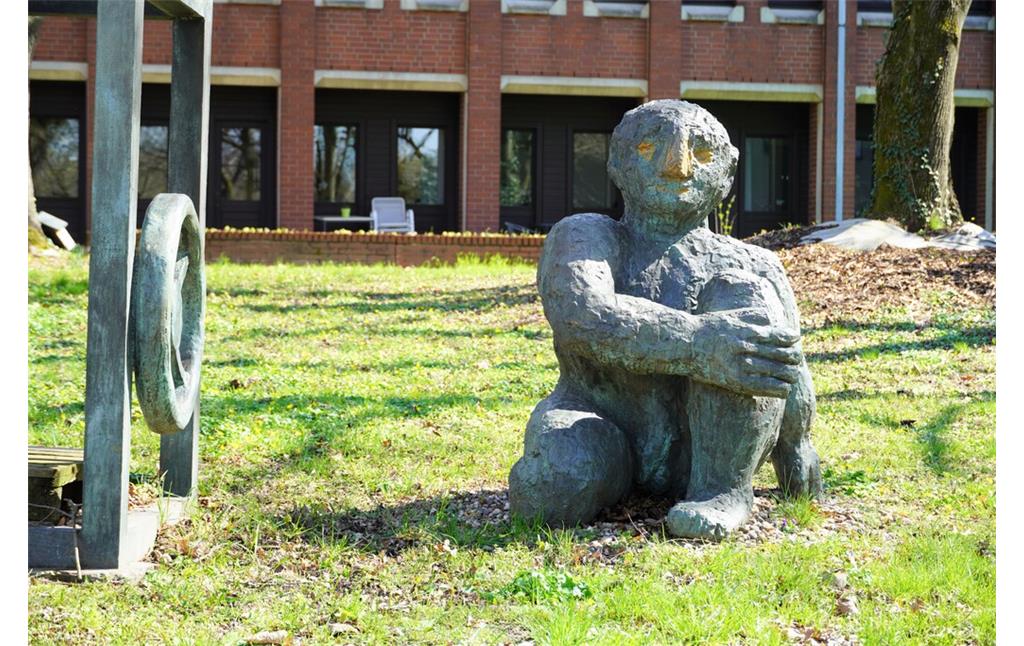 Rechte Figur der Skulpturengruppe "Menschen am Tresor" von Klaus Kampert im Rathauspark in Köln-Porz (2023).