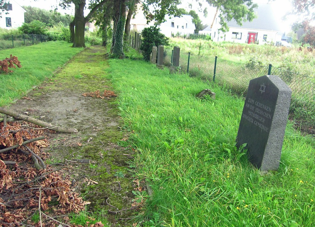 Blick über den jüdischen Friedhof in Hülchrath von der Pforte aus - im Vordergrund ein Gedenkstein und im Hintergrund einzelne Grabsteine (2014).