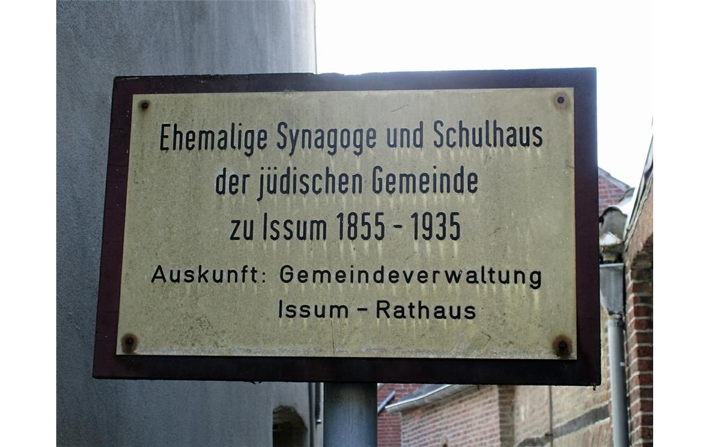 Hinweisschild, welches auf die ehemalige Synagoge mit jüdischer Mikwe (Ritualbad) und Schulhaus, heute Gedenkstätte in der  Kapellener Straße in Issum, hinweist (2016).