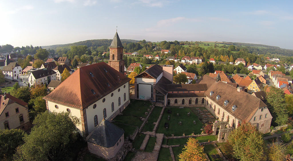 Luftaufnahme der gesamten Klosteranlage Hornbach. Links die Klosterkirche, rechts Teile des ehemaligen Kreuzgangs und links unten, am Ende der Kirche, die neuzeitliche Kapelle über dem Pirminiusgrab (2015).