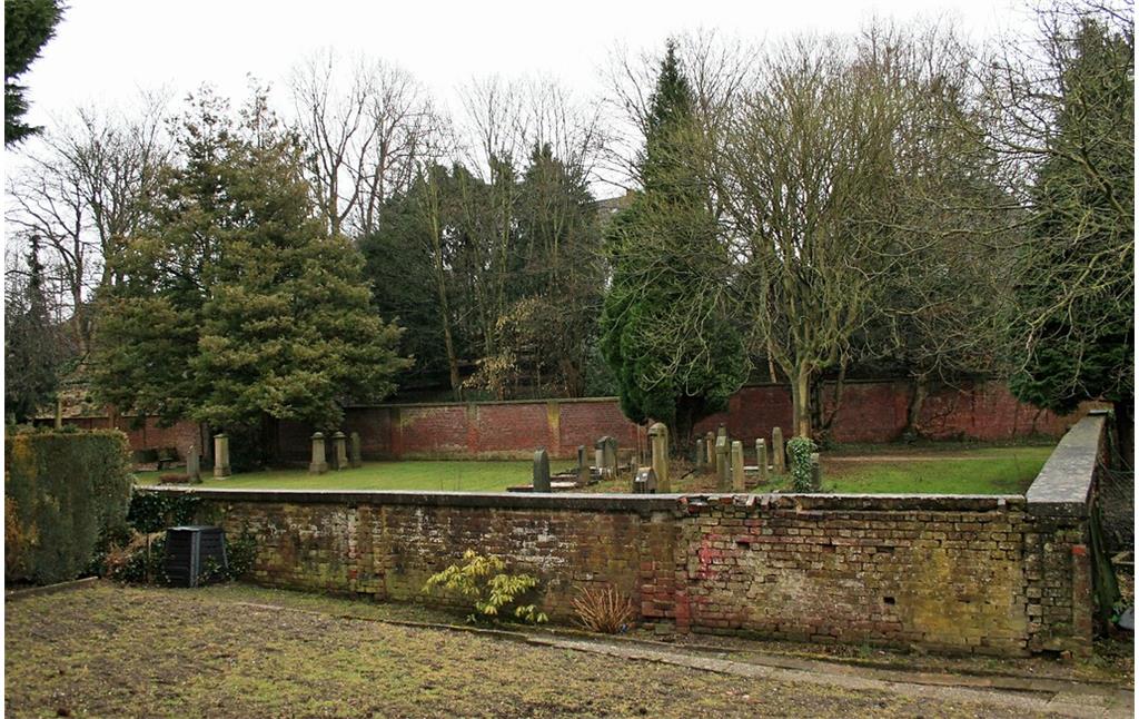 Blick auf das Gräberfeld des Judenfriedhofs Roßweide in Mönchengladbach-Wickrath (2015), hier die Sicht auf den verschlossenen Friedhof von einem benachbarten Parkplatz aus.