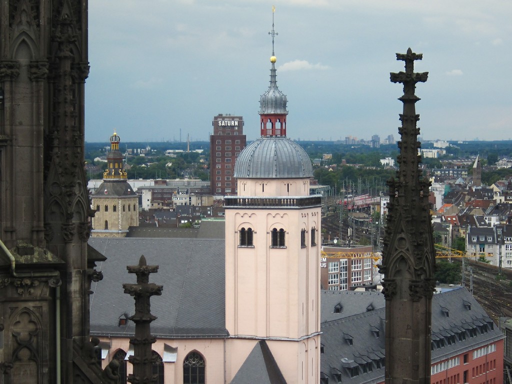 Kirchturm des Jesuitenkollegs Sankt Mariä Himmelfahrt in Köln, dahinter links der Turm des Ursulastifts und das Saturn-Hochhaus (Hansahochhaus), Ansicht vom Dach des Kölner Doms aus (2014).