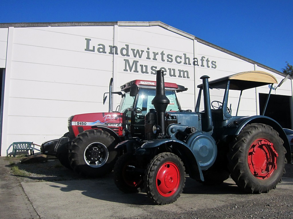 Ein historischer "Lanz"-Bulldog vor einem modernen Traktor "Case" am Eingang zum Landwirtschaftsmuseum in der Gehöftgruppe Sinsteden bei Rommerskirchen (2014).