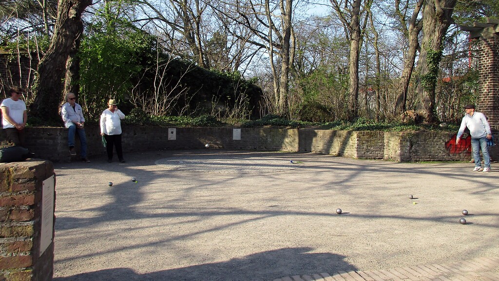 Boulespieler an dem der Friedenshymne "Imagine" von John Lennon gewidmeten Denkmal im Kölner Friedenspark im Inneren Grüngürtel (2022).