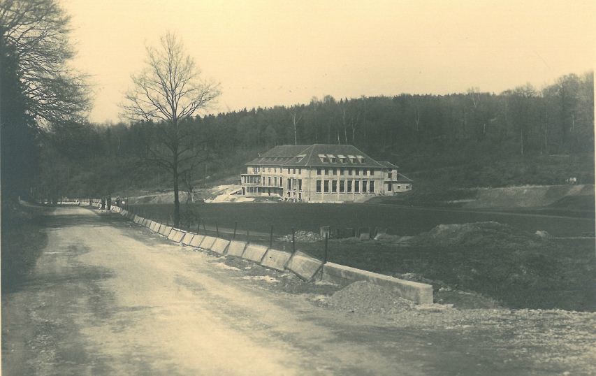Straßenarbeiten an der Sövener Straße im Dürresbachtal bei Hennef, im Hintergrund der Rohbau der Sportschule, Ansicht von Süden (Aufnahme 1949).