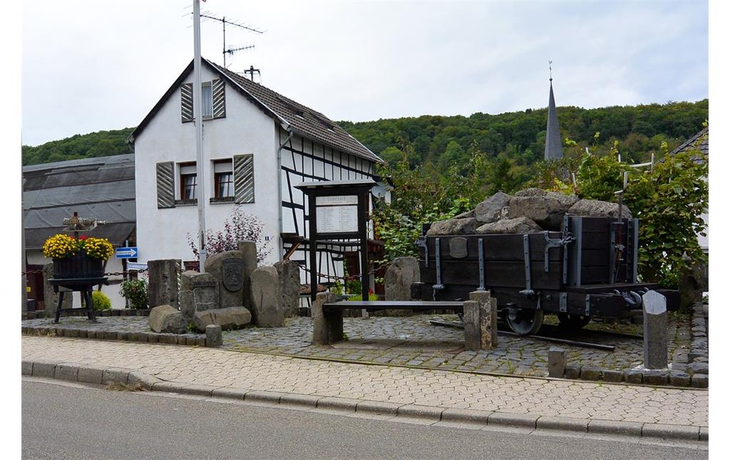 Dorfplatz in Remagen-Unkelbach mit einer Lore aus dem nahen Steinbruchbetrieb und einer Weinpresse (2014)