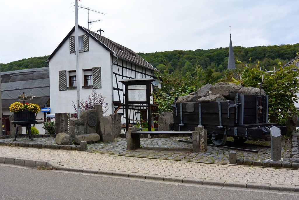 Dorfplatz in Remagen-Unkelbach mit einer Lore aus dem nahen Steinbruchbetrieb und einer Weinpresse (2014)