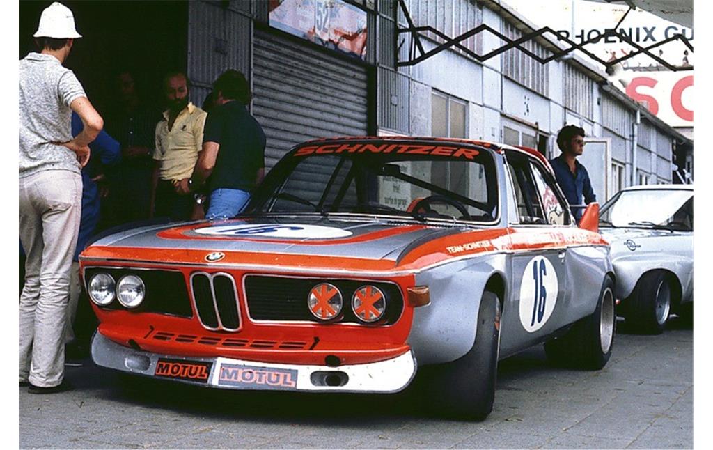 Rennwagen des Typs BMW Schnitzer CSL mit den Autorennfahrern Henry Pescarolo (gelbes Hemd) und Vittorio Brambilla (blaue Hose) im Fahrerlager des Nürburgrings (1973)